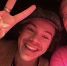 two people are smiling and making the peace sign with their fingers in front of them