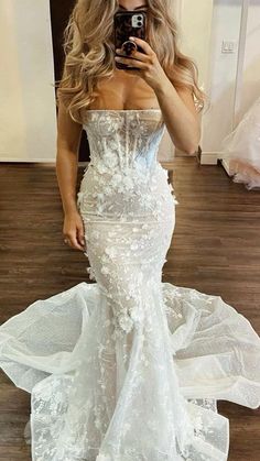 a woman taking a selfie in a wedding dress with her phone up to her face