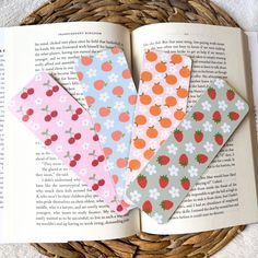 four bookmarks in the shape of strawberrys and daisies on top of an open book