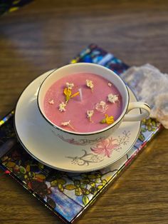 a bowl of soup is sitting on a plate next to a napkin with flowers in it