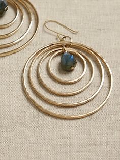 A stellar example of radiant beauty, hammered brass rings intersect in three dimensions and orbit luminescent, faceted labradorite stones on dangling hoop earrings.  ECLECTIC STONE COLLECTION: Crafted in graceful, free form shapes, the Eclectic Stone Radiant Beauty, Hammered Jewelry, Brass Rings, Dangle Hoop Earrings, Hammered Brass, Semi Precious Gems, Stone Collection, Blue Labradorite, Women's Jewelry And Accessories