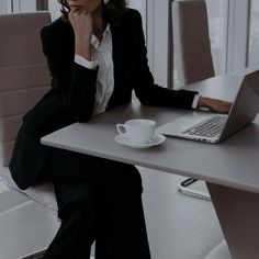 a woman sitting at a table with a laptop and coffee cup in front of her