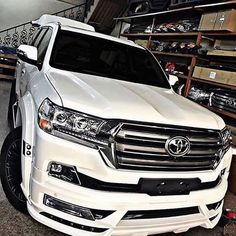 a white suv parked in a garage next to some shelves filled with tools and other items