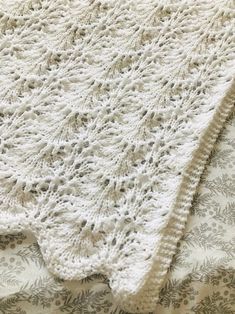 a white crocheted blanket sitting on top of a bed