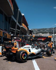 an orange and white race car sitting in the pit