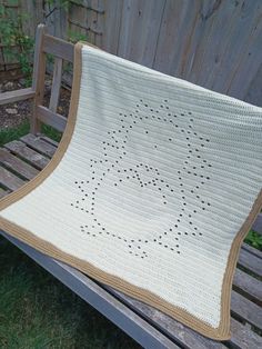 a crocheted blanket sitting on top of a wooden bench