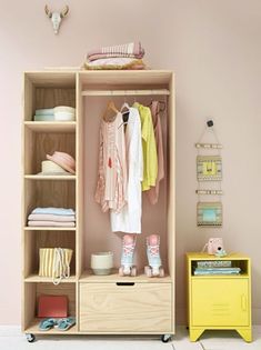 a child's wardrobe with clothes and toys on it in a pink walled room
