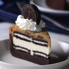 a piece of oreo cake on a white plate with a cookie and whipped cream topping