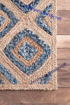 a blue and beige area rug on top of a wooden floor next to a vase