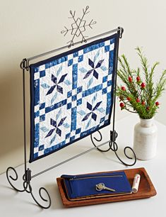 a blue and white quilt sitting on top of a table next to a potted plant