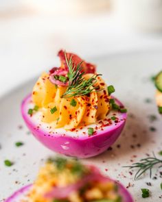 deviled eggs topped with cheese and garnish on a white plate