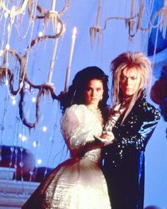 two women standing next to each other in front of chandelier