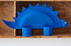 a blue paper plate shaped like a dinosaur in a wooden box with two smaller plastic cups