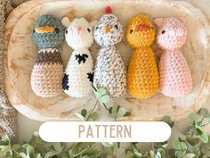 four crocheted stuffed animals sitting on top of a wooden tray next to green plants
