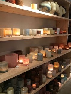 many lit candles on shelves in a store