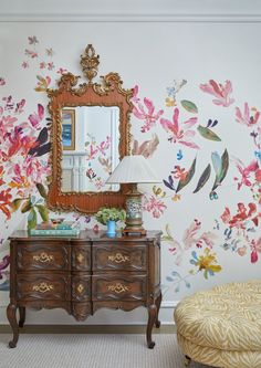 an ornate dresser and mirror in front of a floral wallpaper