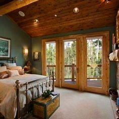 a bedroom with green walls and wood ceilinging has a large bed in the middle