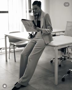 a man in a suit sitting at a table while talking on a cell phone and holding a clipboard