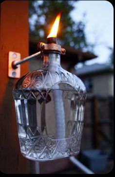 a glass bottle with a candle in it hanging from a hook