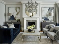 a living room filled with furniture and a chandelier hanging from the ceiling over a fire place