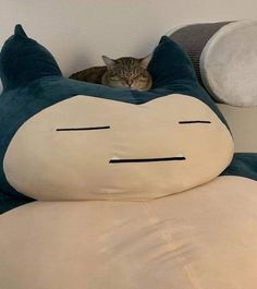 a cat is sleeping on top of a pillow shaped like a cartoon character with eyes closed