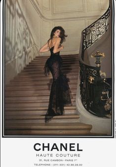 a woman in a black dress standing on some stairs