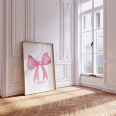 an empty room with a pink bow on the wall and a framed poster in front of it