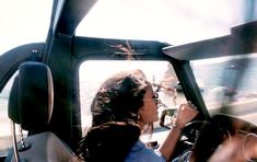 a woman sitting in the driver's seat of a car looking out at the ocean