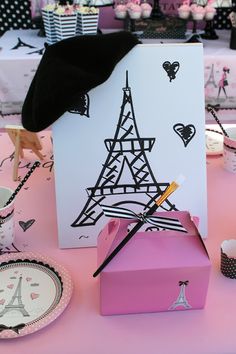 a table topped with pink boxes and plates next to a black umbrella on top of it