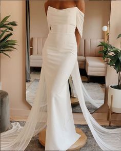 a woman in a white wedding dress looking at herself in the mirror with her veil flowing