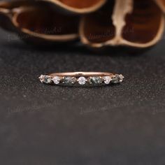 an image of a wedding band with stones on it and a shoe in the background