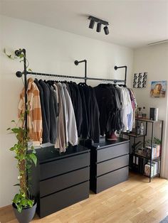 an organized closet with clothes hanging on the rail and two planters next to it