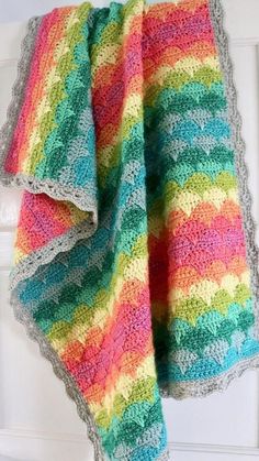 a multicolored crocheted blanket hanging on a door handle next to a white door
