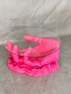 a pink plastic figurine laying on top of a glass table
