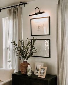 a black and white living room with pictures on the wall, plants in vases