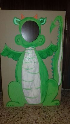 a cardboard box with a green dragon painted on it's face and arms, standing in front of a wall