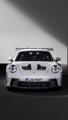 a white sports car is parked in front of a large wall with lights on it