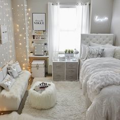a bedroom decorated in white and gray with lights on the walls, bedding, rugs and pillows