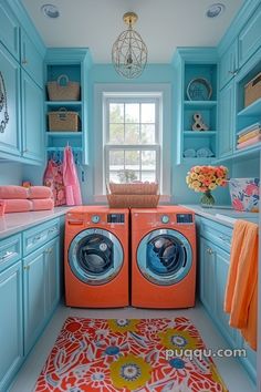 a washer and dryer are in the corner of this laundry room with blue cabinets