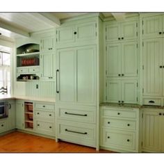 a kitchen with white cabinets and wood floors