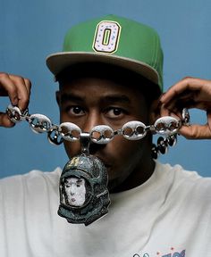 a man wearing a green hat and chain around his neck with a helmet on it