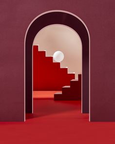 an arch leading into a red room with stairs and a white ball in the middle