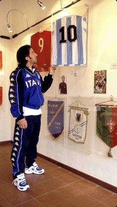 a young man holding up a blue and white jersey in front of a display case
