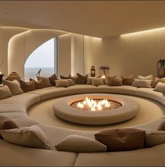 a living room filled with lots of furniture and a fire pit in the middle of it