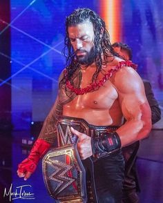 a man with long hair and beard holding a wrestling belt