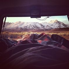 the view from inside a vehicle looking out at mountains and grass in the foreground