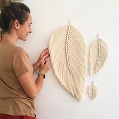 a woman is working on an art piece that looks like a leaf and two smaller leaves are attached to the wall