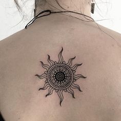 a woman's back with a sun tattoo on it