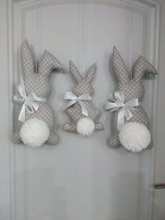 three stuffed bunnies hanging on the door with white polka dotty bows and pom - poms