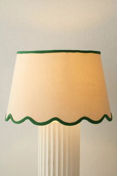 a white lamp with a green trim around the base and a beige shade on top